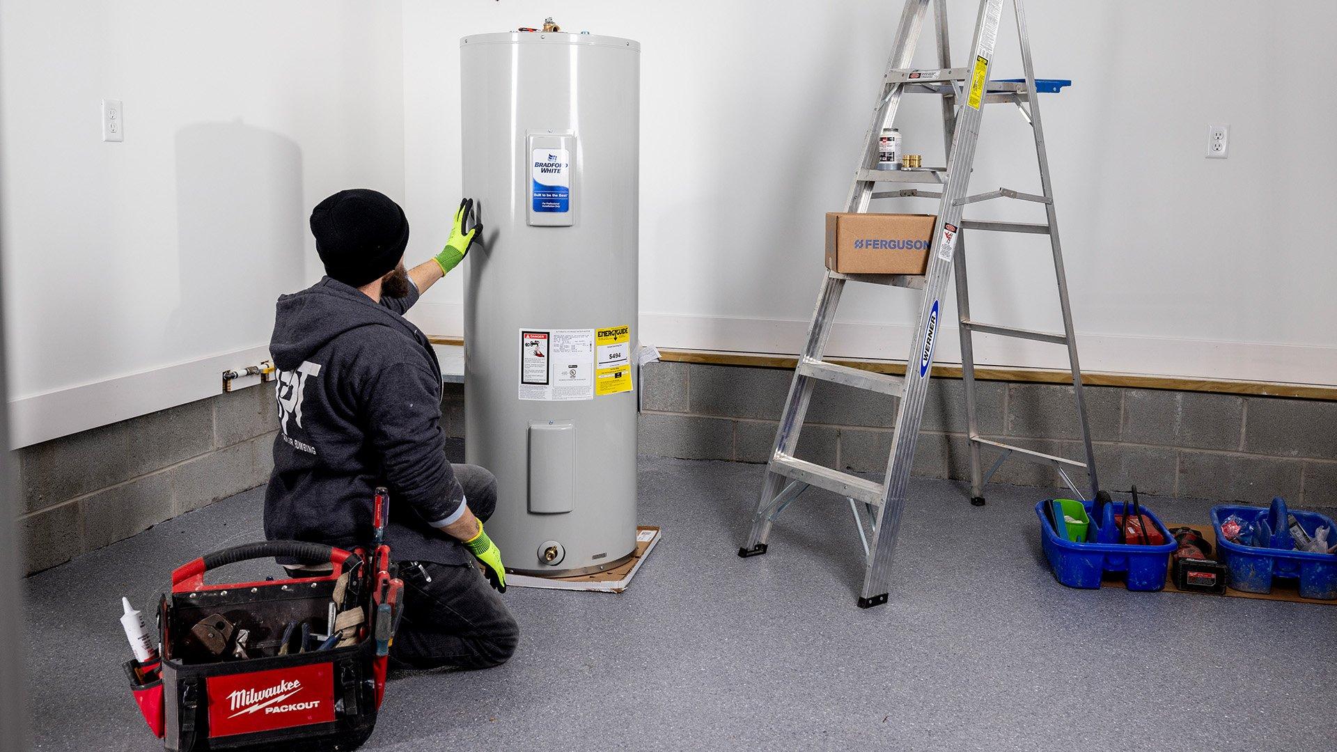 Technician installs Bradford White residential water heater in garage. 